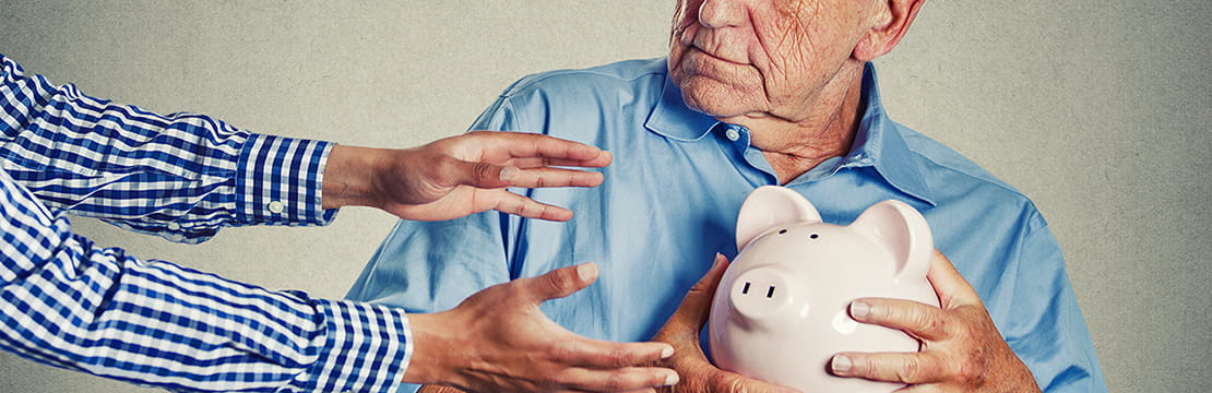 Close up portrait of elderly man holding piggy bank, looking suspicious trying to protect his savings from being stolen from outstretched arms. Financial fraud concept